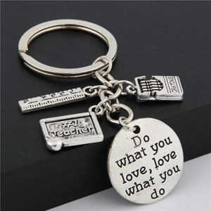 Macro shot of silver metal keychain with ruler, crayons, and blackboard pendants for teachers