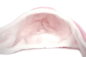 Dettaglio della fodera in peluche rosa e della morbida consistenza di un cappello da neonato