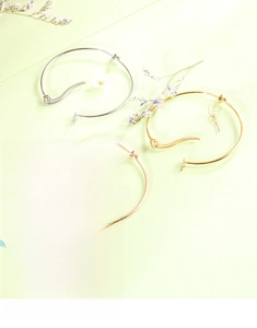 Close-up of minimalist knot hoop earrings in polished gold and silver finishes