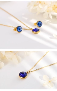 Macro detail of gold necklace and round blue sapphire studs on white flower petals