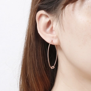 Elegant rose gold twisted rope hoop earrings for women worn by a model in a minimalist style