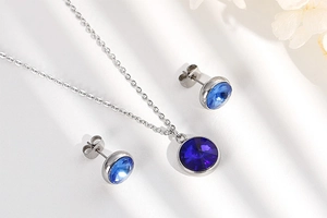 Silver jewelry set featuring round blue zircon pendant and matching earrings with floral accents