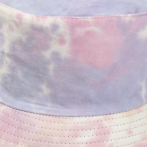 Detailed macro view showing the purple tie-dye pattern and fine stitching on cotton bucket hat