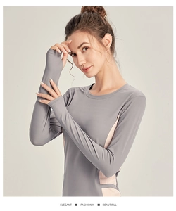 Détail du haut de sport gris à manches longues avec empiècements roses et passe-pouces