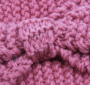 Close-up of thick knit headband texture in dark pink with a stylish bow design detail