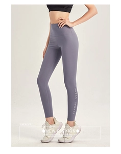 Dettaglio dei leggings viola a vita alta con stampa Urban Sports bianca sulla gamba sportiva