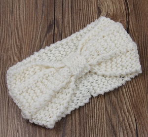 Macro detail of creamy white chunky knit winter headband with central bow twist design