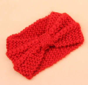 Detail of red cable knit winter headband featuring a classic center bow knot design