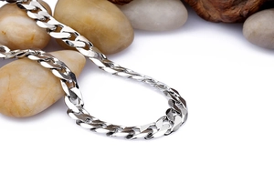 Detailed close-up of 7mm silver diamond-cut curb chain necklace on natural river stones