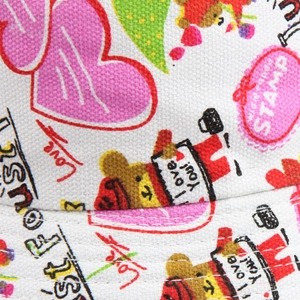 Detailed close-up of floral canvas fabric with cute bear and heart prints for sun hats