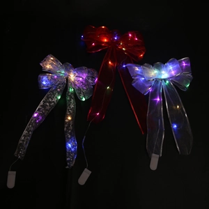 Detail of silver LED glowing Christmas bows with battery pack on black background