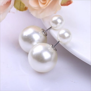 Gros plan détaillé de boucles d'oreilles perles double face crème sur porcelaine blanche