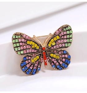 Detailed view of golden butterfly brooch with colorful rhinestones on a white background