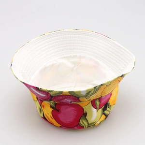Detail of children's cotton bucket hat featuring vibrant red apple and green pear patterns