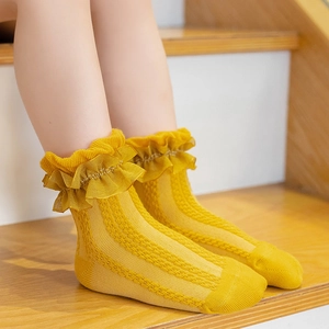 Girls' yellow cotton lace socks with mesh design shown on feet over wooden stairs