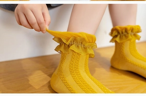 Detail of yellow knit socks for girls featuring lace trim and breathable mesh texture