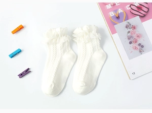 Close-up of white baby socks featuring delicate lace ruffles and soft knitted texture