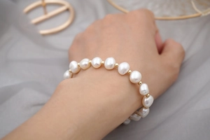 Detailed view of Baroque freshwater pearls with gold bead spacers on a woman's wrist