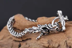 Détail d'un bracelet tête de dragon en acier titane argenté sur un support en bois