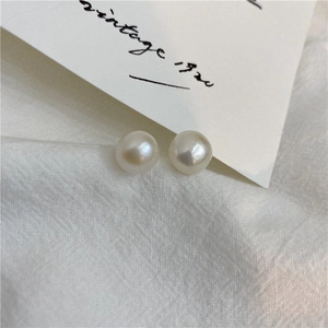 Macro shot of white freshwater pearl earrings on vintage linen and calligraphy card