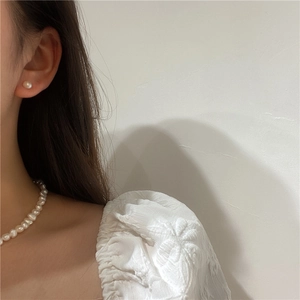Close-up of elegant white freshwater pearl necklace and stud earrings worn by a model