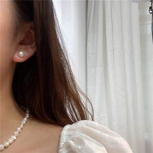 Detail of natural freshwater pearl stud earrings and necklace worn on model