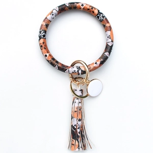 Close-up of leather keyring wristlet featuring dog pattern, fringe tassel and gold clasp