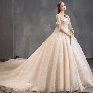Elegant champagne off-shoulder wedding dress with lace embroidery and a long royal train