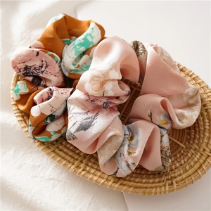 Detail of satin floral scrunchies in pink and orange placed in a wicker basket