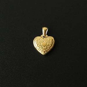 Macro detail of a 18K gold-plated heart pendant with fine vintage engraved carvings