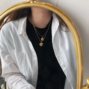 Close-up of 18K gold plated heart and coin pendants on a model in vintage style