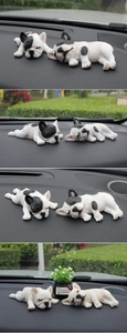 Detailed close-up of sleeping French Bulldog car ornaments on a dashboard