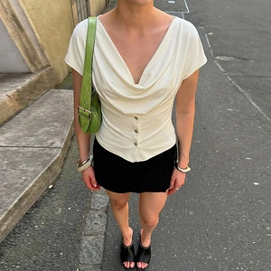 Detail of cowl neck design on slim fit off-white short sleeve top with button accents
