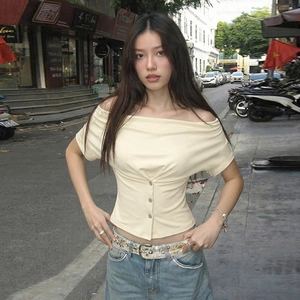 Close-up of cream off-shoulder slim T-shirt featuring pleated bust and decorative buttons