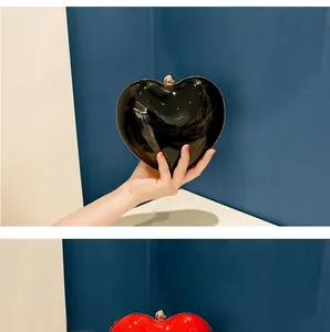 Close-up of heart-shaped acrylic evening clutch bags in glossy red and black finishes