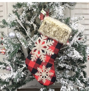 Detail of red and black plaid Christmas stocking with gold glitter snowflakes on a tree