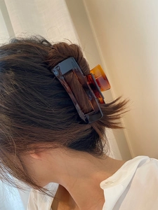 Close-up of a large amber tortoiseshell hair claw clip securing a bun on model back head