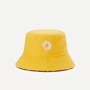 Detailed close-up of yellow bucket hat with white daisy floral embroidery and stitched brim