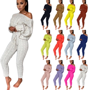 Dettaglio del maglione in maglia a trecce con spalle scoperte e pantaloni coordinati