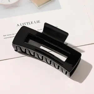 Close-up of a large black rectangle hair claw clip with a glossy finish on a minimalist card