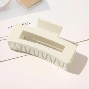 Detail of a large matte cream hair claw clip with a minimalist hollow rectangular design