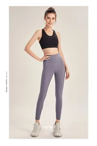 Full view of black sports bra and mauve high waisted yoga pants with lace-up sneakers