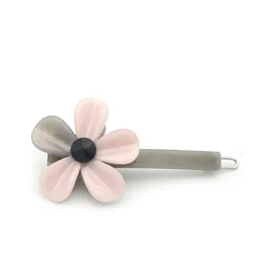 Pince à cheveux fleur en acétate avec pétales roses et centre noir sur fond blanc