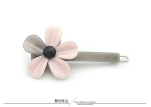 Détail de la pince à cheveux fleur en acétate avec pétales roses et fermoir métallique