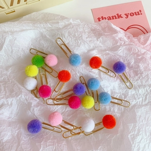 Colorful plush ball paper clips on white textured paper with a pink thank you card