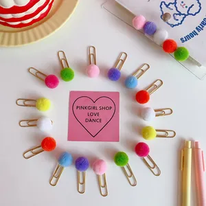 Detail of colorful plush pom pom paperclips arranged in a ring on a white background