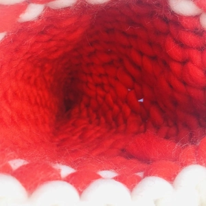 Close-up of thick chunky knit texture on red and white handmade Christmas hat