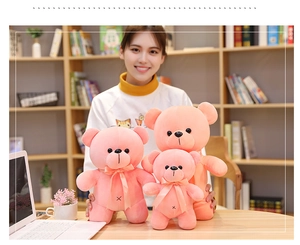 Three sizes of pink plush teddy bears with neck ribbons shown in a cozy home study room