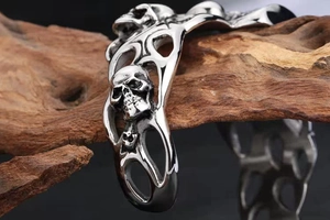 Close-up of 3D skull engraving and hollow floral patterns on a silver punk bracelet