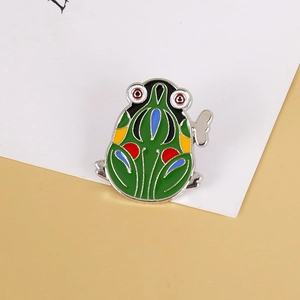 Macro shot of green enamel clockwork frog brooch with geometric patterns on card